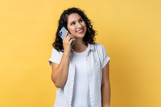 Glimlachende tevreden vrouw die staat en praat op smartphone die goed nieuws hoort