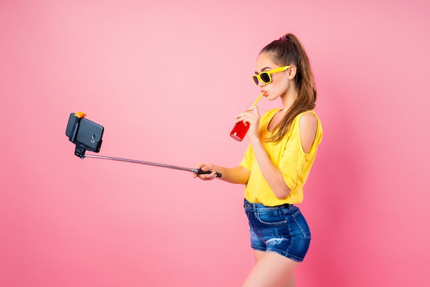 Glimlachende tiener die met drank selfie met stok maakt