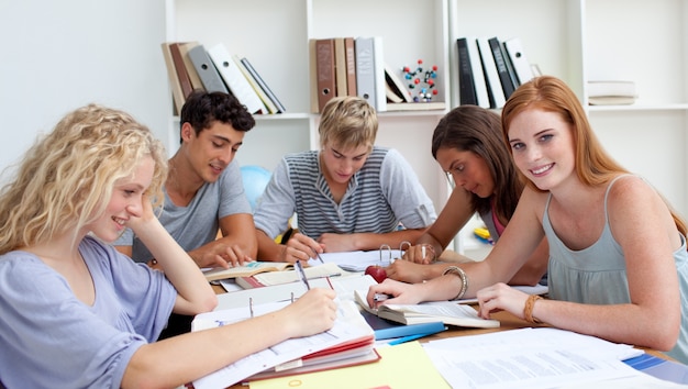 Glimlachende tieners die in de bibliotheek bestuderen