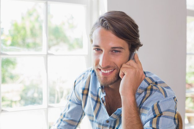 Glimlachende toevallige mens die op smartphone spreekt