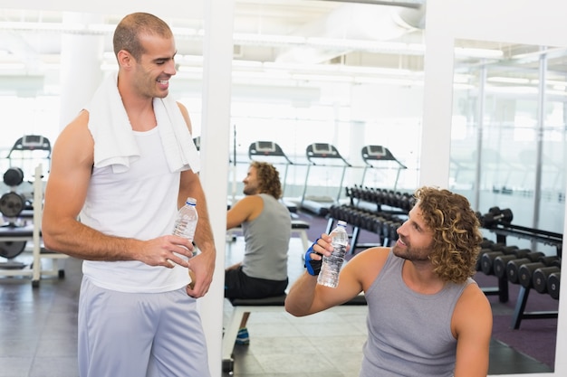 Glimlachende trainer die aan de geschikte mens bij gymnastiek spreken