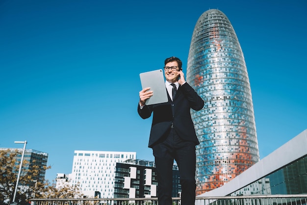 Glimlachende trendy man met behulp van tablet en praten over de telefoon