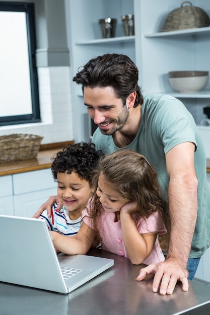 Glimlachende vader die laptop met zijn kinderen met behulp van