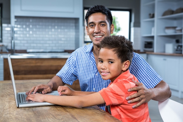 Glimlachende vader die laptop met zijn zoon met behulp van