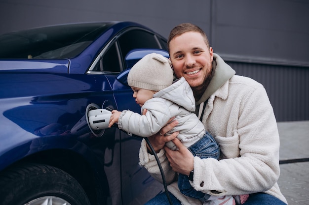 Glimlachende vader en dochter die elektrische auto thuis opladen