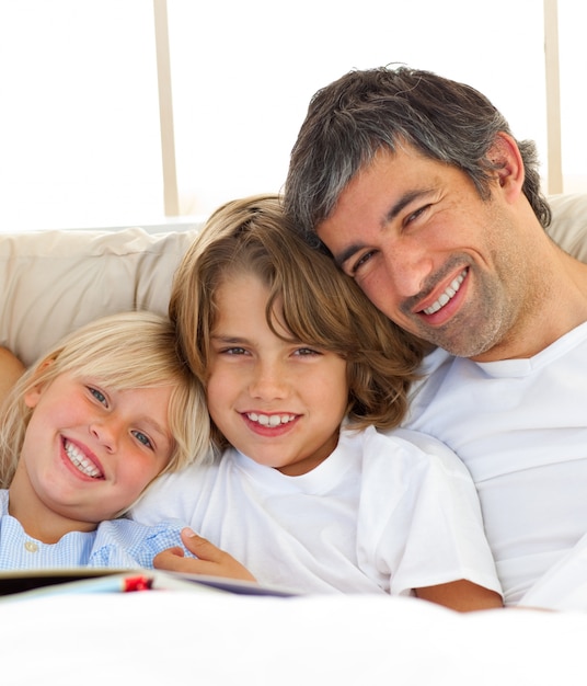 Glimlachende vader en zijn kinderen die boek lezen