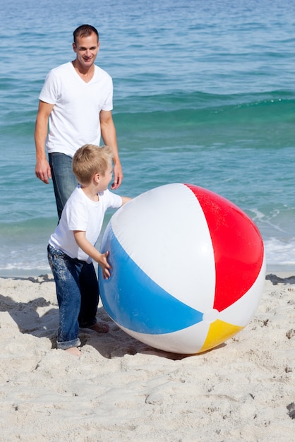 Glimlachende vader en zijn zoon die met een bal spelen