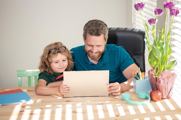 Glimlachende vader en zoon gebruiken thuis moderne technologie. familie blog.