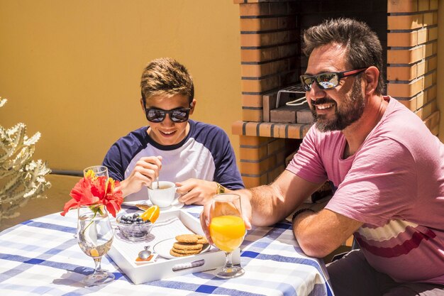 Foto glimlachende vader en zoon met ontbijt op tafel