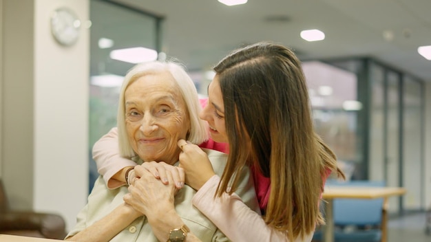 Glimlachende verpleegster omhelst een oudere vrouw in de geriatrie