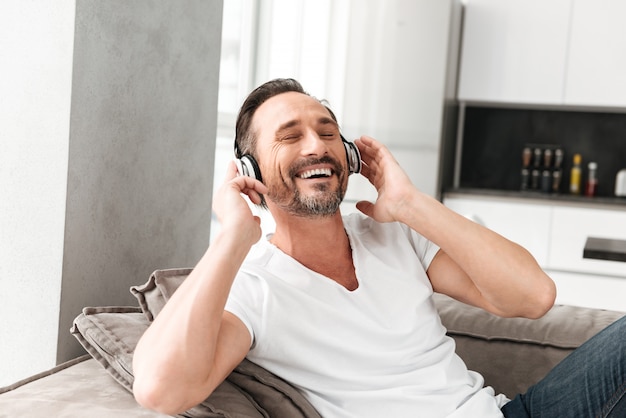 Glimlachende volwassen mens die aan muziek met hoofdtelefoons luistert