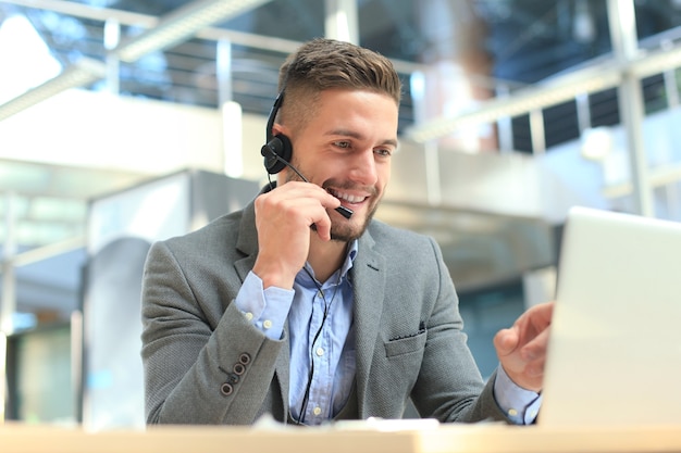 Glimlachende vriendelijke knappe jonge mannelijke callcenter-operator.