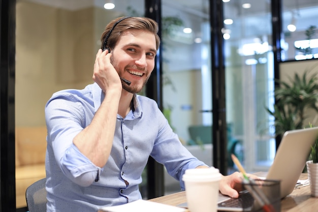 Glimlachende vriendelijke knappe jonge mannelijke callcenter-operator.