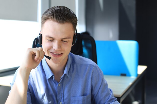 Glimlachende vriendelijke knappe jonge mannelijke callcenter-operator.