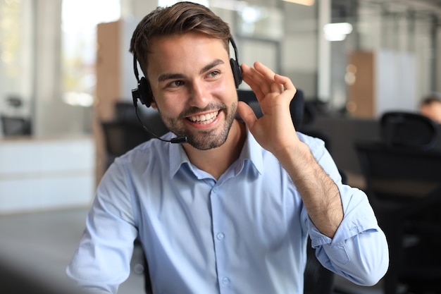 Glimlachende vriendelijke knappe jonge mannelijke callcenter-operator.