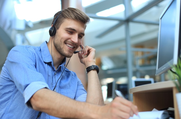 Glimlachende vriendelijke knappe jonge mannelijke callcenter-operator.