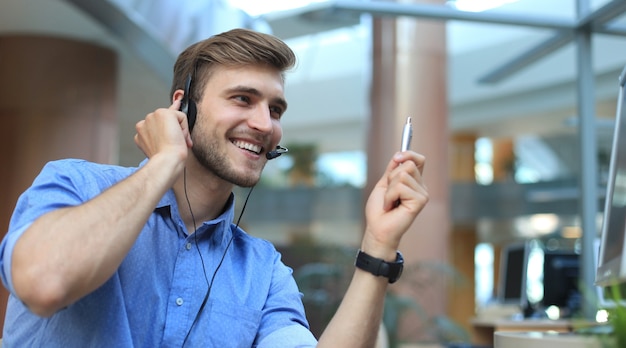 Glimlachende vriendelijke knappe jonge mannelijke callcenter-operator.