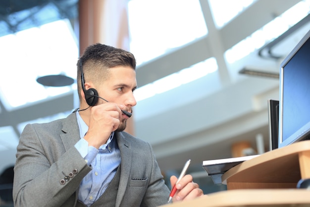 Glimlachende vriendelijke knappe jonge mannelijke callcenter-operator.