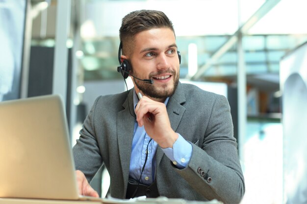 Glimlachende vriendelijke knappe jonge mannelijke callcenter-operator.