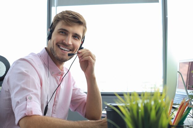 Glimlachende vriendelijke knappe jonge mannelijke callcenter-operator.