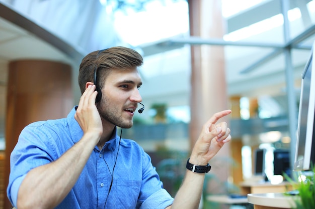 Glimlachende vriendelijke knappe jonge mannelijke callcentermedewerker