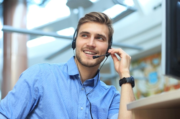 Glimlachende vriendelijke knappe jonge mannelijke callcentermedewerker