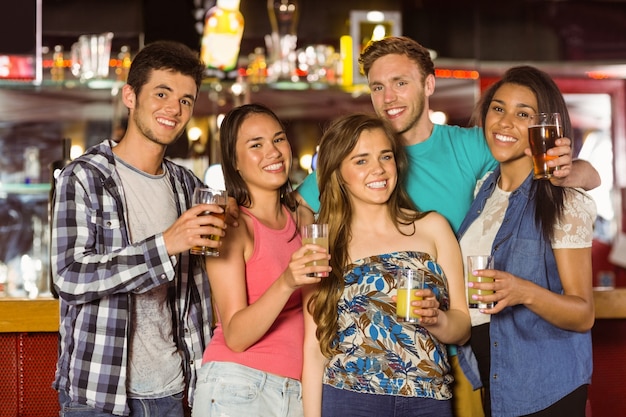 Glimlachende vrienden die bier en gemengde drank drinken