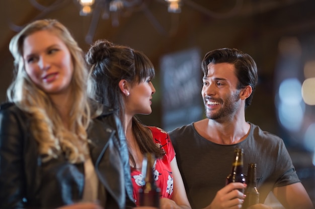 Glimlachende vrienden die elkaar aankijken terwijl ze bierflesjes vasthouden