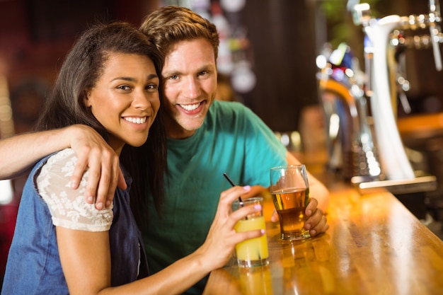 Glimlachende vrienden die en bier en gemengde drank spreken drinken