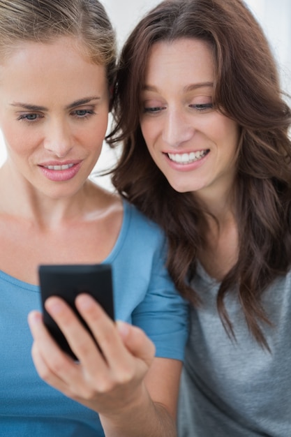 Foto glimlachende vrienden die mobiele telefoon bekijken