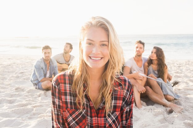 Glimlachende vrienden die op zand zitten