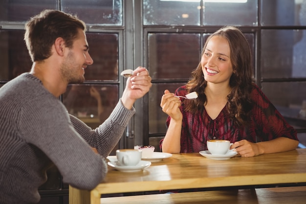 Glimlachende vrienden die van koffie en cake samen genieten