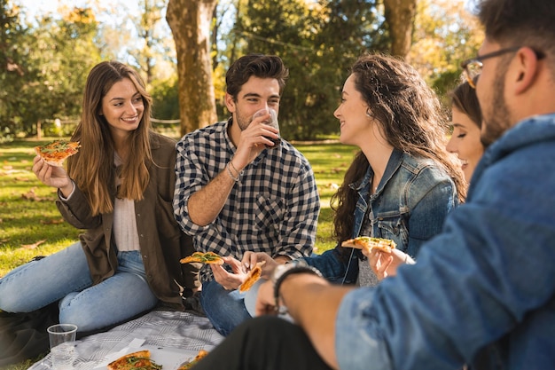 Glimlachende vrienden eten eten in een picknick in het park