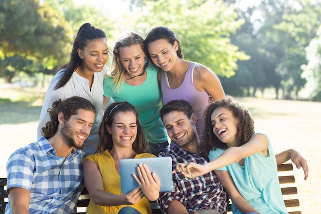 Glimlachende vrienden in het park die tabletpc met behulp van