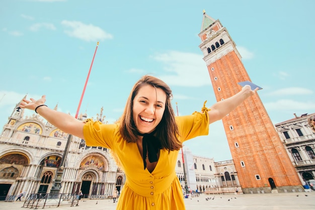 Glimlachende vrolijke vrouw in gele zomerjurk voor de basiliek van San Marco in Venetië