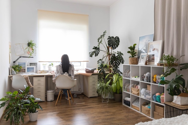 Glimlachende vrouw bekwame kleermaker kleding productieproces op naaimachine poseren op een comfortabele thuiswerkplek Vrouwelijke modeontwerper kleding stof workshop handmatige steek kledingmaker werkruimte