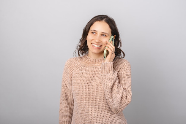 Glimlachende vrouw belt via de telefoon Portret over grijze achtergrond