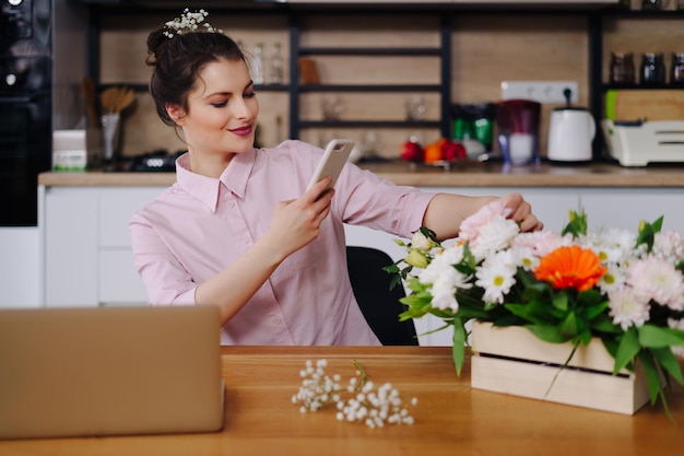 Glimlachende vrouw Bloemist Klein bedrijf Eigenaar bloemenwinkel Ze gebruikt haar telefoon en laptop om bestellingen op te nemen voor haar online winkel Foto's maken