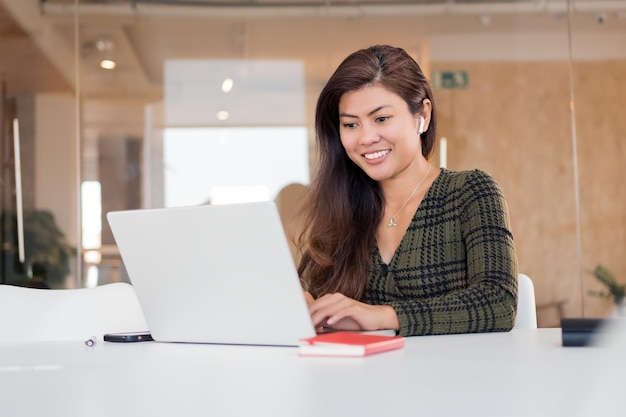 Glimlachende vrouw die aan laptop in bureau werkt