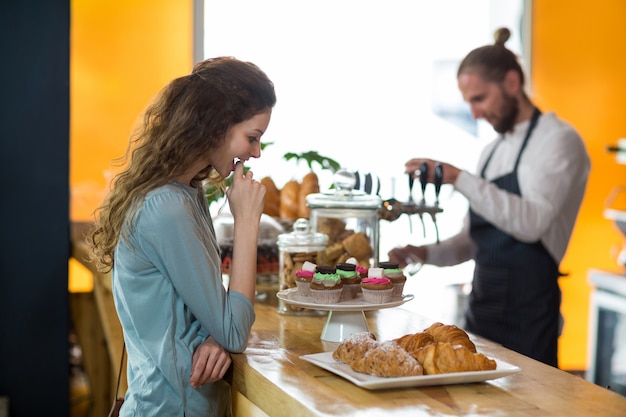 Glimlachende vrouw die croissant bekijkt