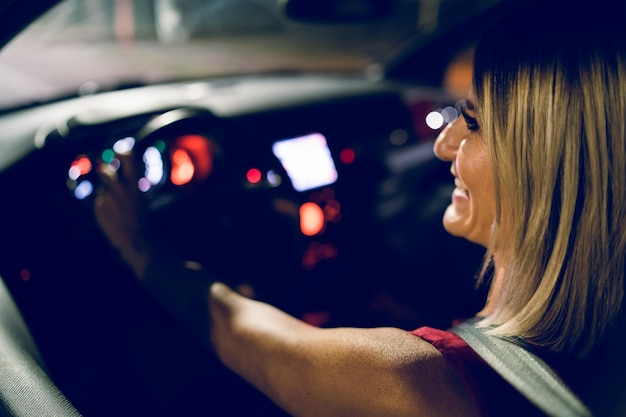 Foto glimlachende vrouw die een auto rijdt.