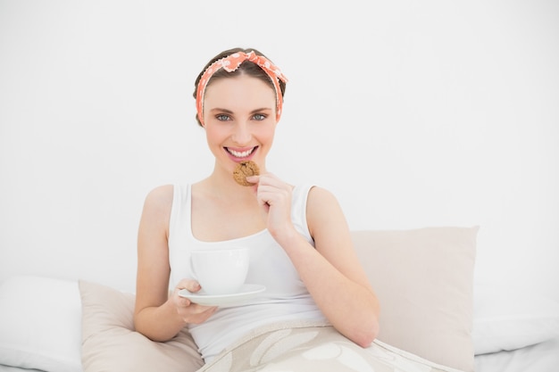 Glimlachende vrouw die een koekje eet