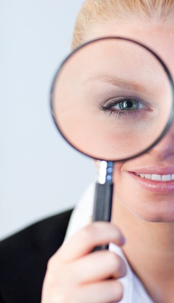 Glimlachende vrouw die een magniying glas onderzoekt