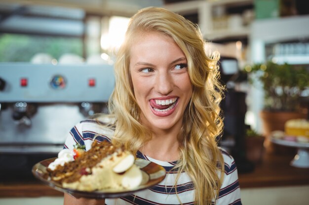 Foto glimlachende vrouw die een plaat van desserts houdt