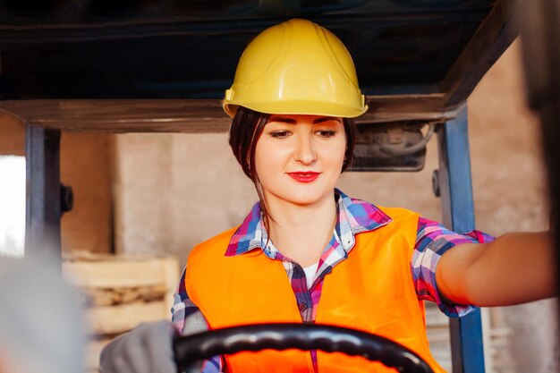 Glimlachende vrouw die een vorkheftruck bestuurt in het magazijn