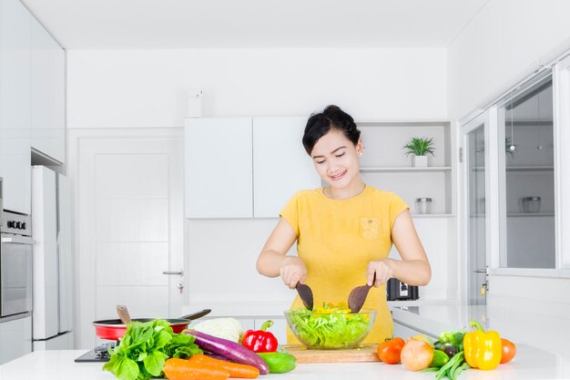 Glimlachende vrouw die eten bereidt terwijl ze thuis in de keuken staat