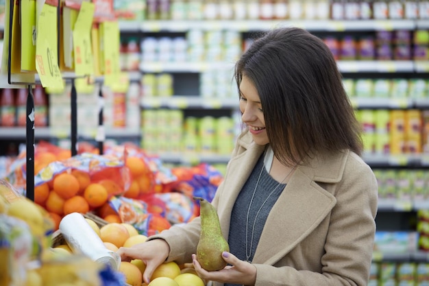 Glimlachende vrouw die fruit koopt in de supermarkt
