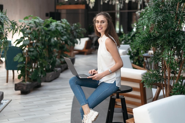 Glimlachende vrouw die haar e-mail leest in een lege cafézaal