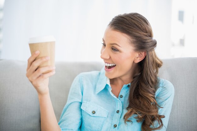 Glimlachende vrouw die haar koffie bekijkt