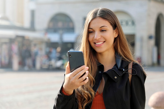 Glimlachende vrouw die haar smartphone gebruikt